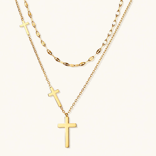 Three-layered gold necklace set with graduated cross pendants in mixed chain styles on white background.